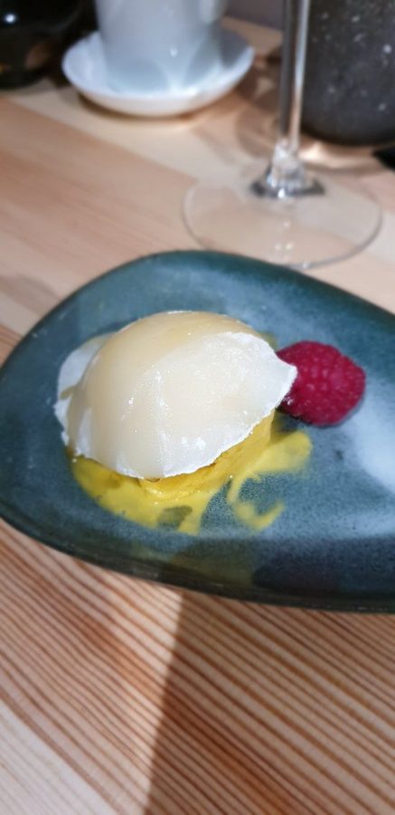 Dolce di riso con lampone e crema, servito su un piatto di ceramica verde.