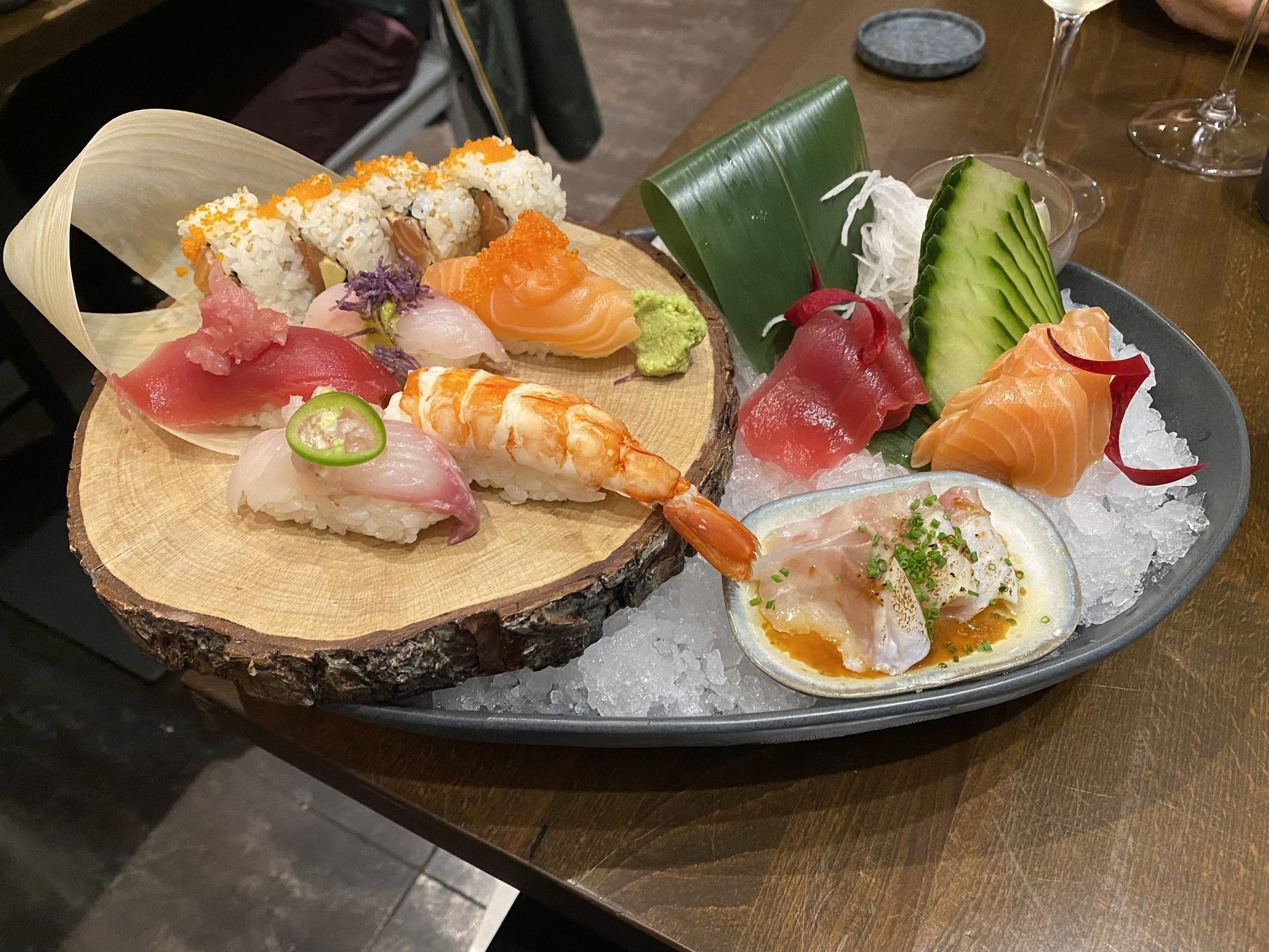 Tagliere di sushi e sashimi: nigiri di salmone, tonno e gambero, uramaki e crudo servito su ghiaccio.