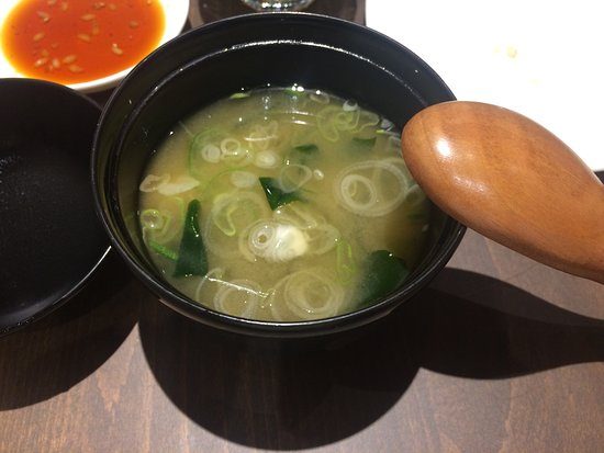 Zuppa di miso in una ciotola nera, con cipollotto e alga.
